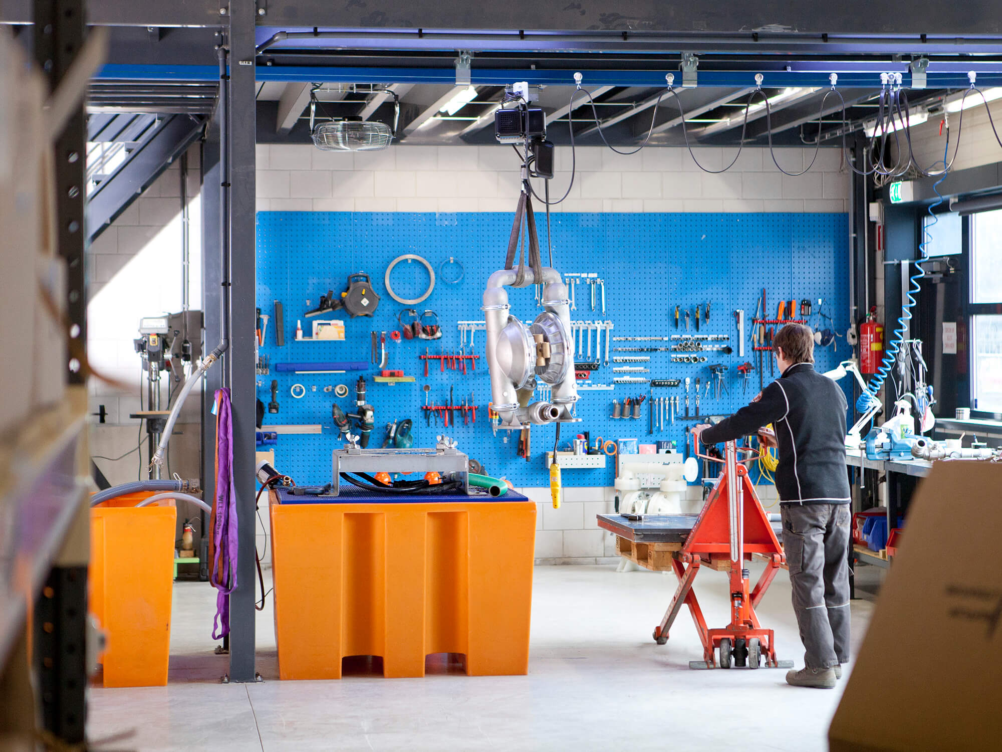 Onze werkplaats: een membraanpomp aan de hijstakel voor het blauwe gereedschapsbord
